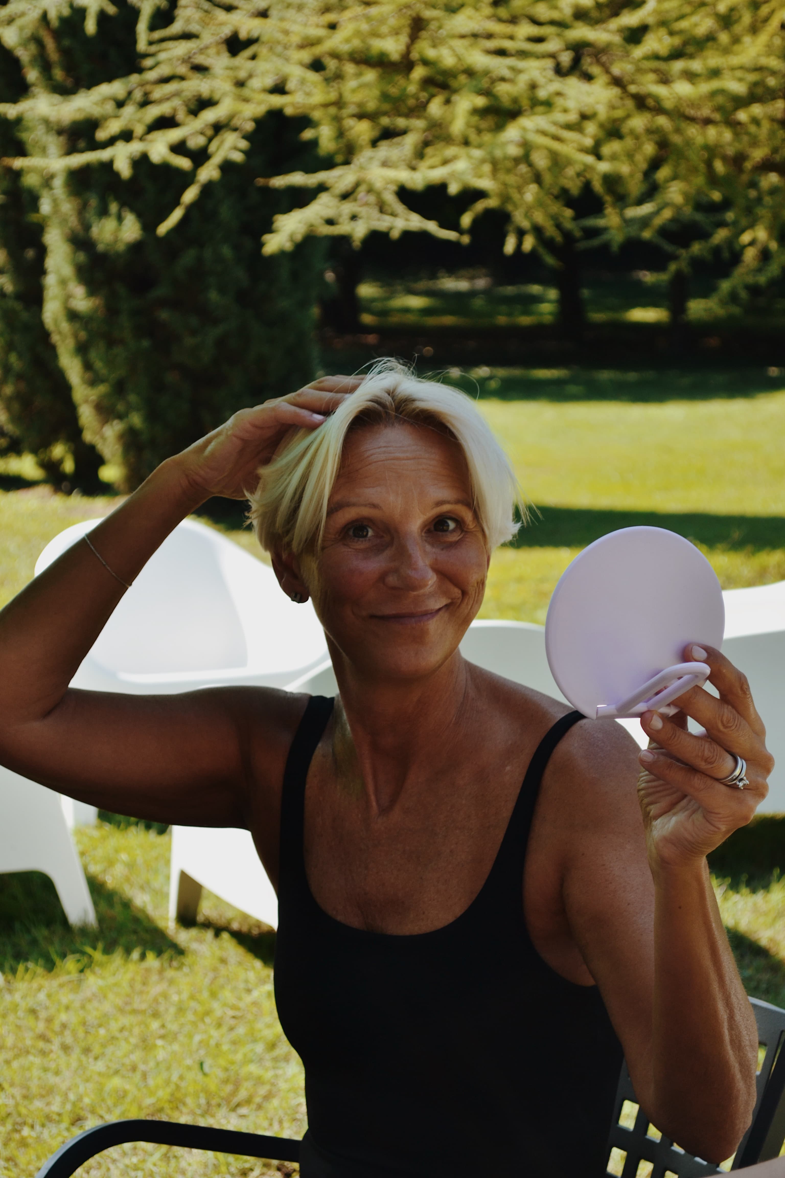 Partecipante applica la skincare routine allo specchio, sorridendo